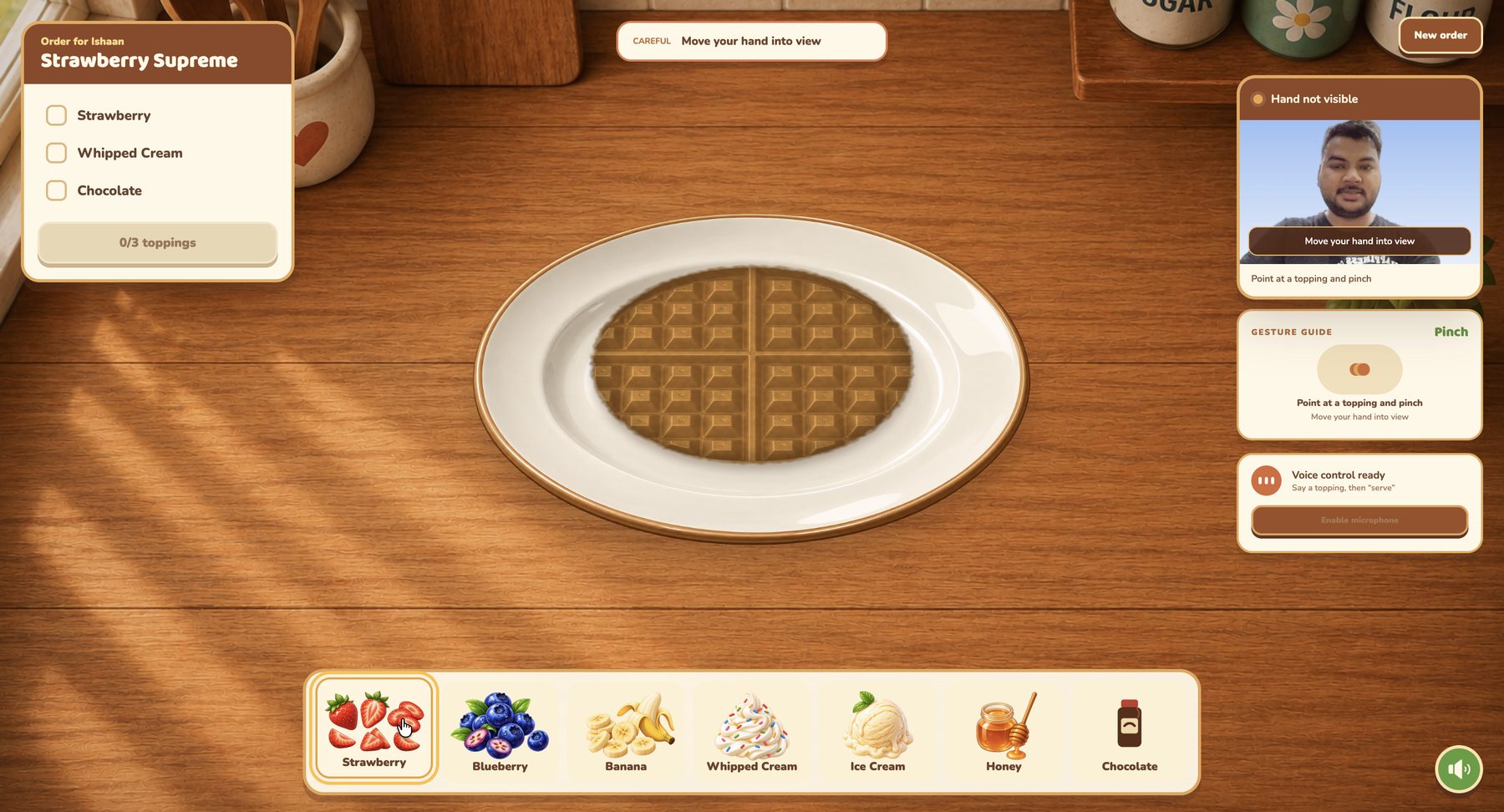 A plain waffle on a plate. An order card for Ishaan lists Strawberry Supreme: strawberry, whipped cream and chocolate. A tray below offers seven toppings. The camera panel warns: hand not visible, move your hand into view.